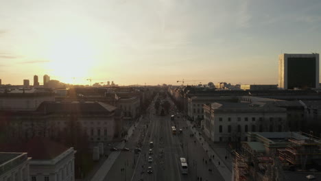 Aéreo:-Vuelo-Panorámico-Bajo-A-Través-De-La-Concurrida-Calle-Berlín,-Alemania-Hacia-La-Puerta-De-Brandenburgo-En-La-Hermosa-Luz-Dorada-Del-Atardecer