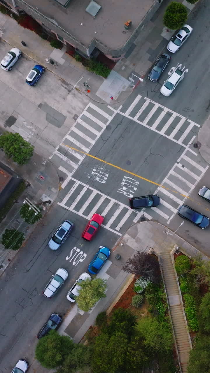 Usual crossroads crossed by private cars in urban city. Top view of the street in San Francisco at daytime. Vertical video