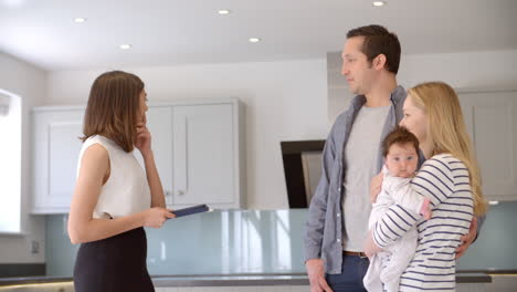 realtor showing young family around property for sale