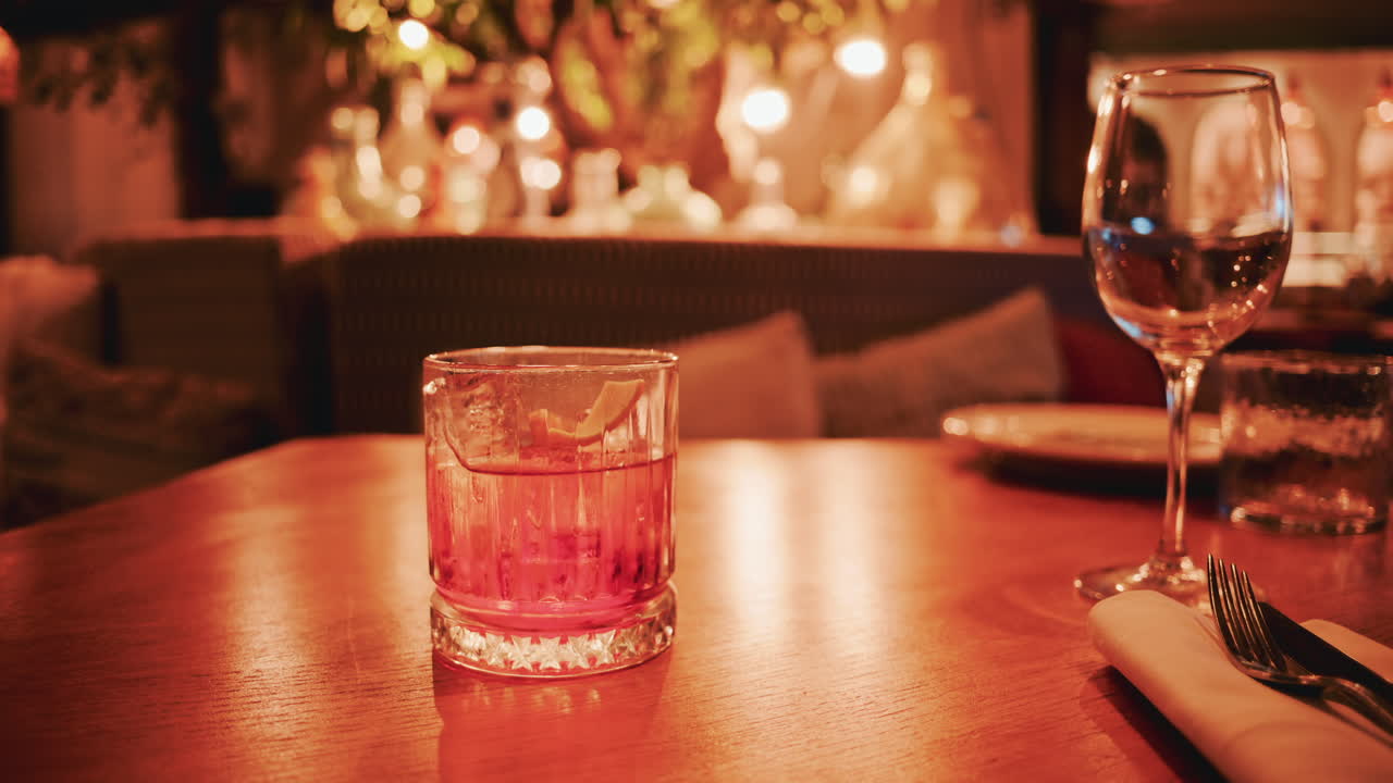 Close up of a cocktail served on a wooden table in a warmly lit restaurant