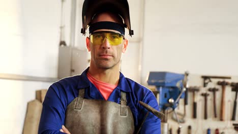 portrait of male welder standing with arms crossed