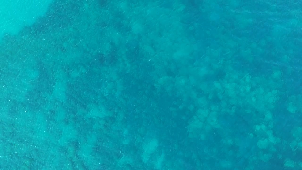 Air biru kehijauan dengan terumbu karang di bawahnya di Pulau Zakynthos, Yunani. Pemandangan udara drone dari atas.