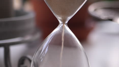 sand aus einer sanduhr fällt in langsamer bewegung auf den hals.