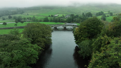 fast wide tracking down through trees and over bridge in yorkshire dales, united kingdom