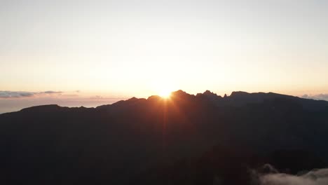 morning sun shines bright over edge of mountains in madeira, aerial