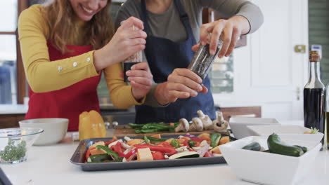 Glückliches-Kaukasisches-Lesbisches-Paar-Bereitet-Essen-In-Sonniger-Küche-Zu