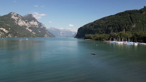 low level altitude flight over the lake in switzerland swiss alpine mountain landscape alps and pine tree forest in highland clouds in the blue sky in spring summer season in europe walensee weesen