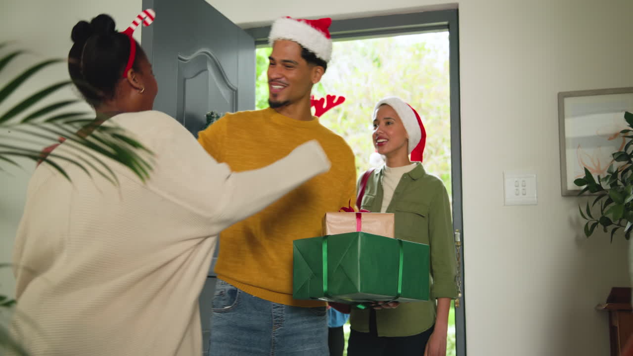 Young diverse friends exchanging gifts at home, celebrating Christmas with joy and laughter