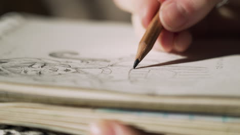 person sketching with pencil, hand-drawing cartoon character on paper, closeup