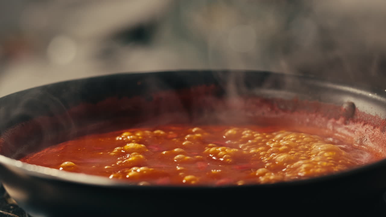 Chicken in tomato sauce is boiling on a frying pan with spices. Cooking tomato sauce curry with chicken fillet. Traditional Italian Mexican Asian dish. High quality studio shot for cafe, restaurant close up.