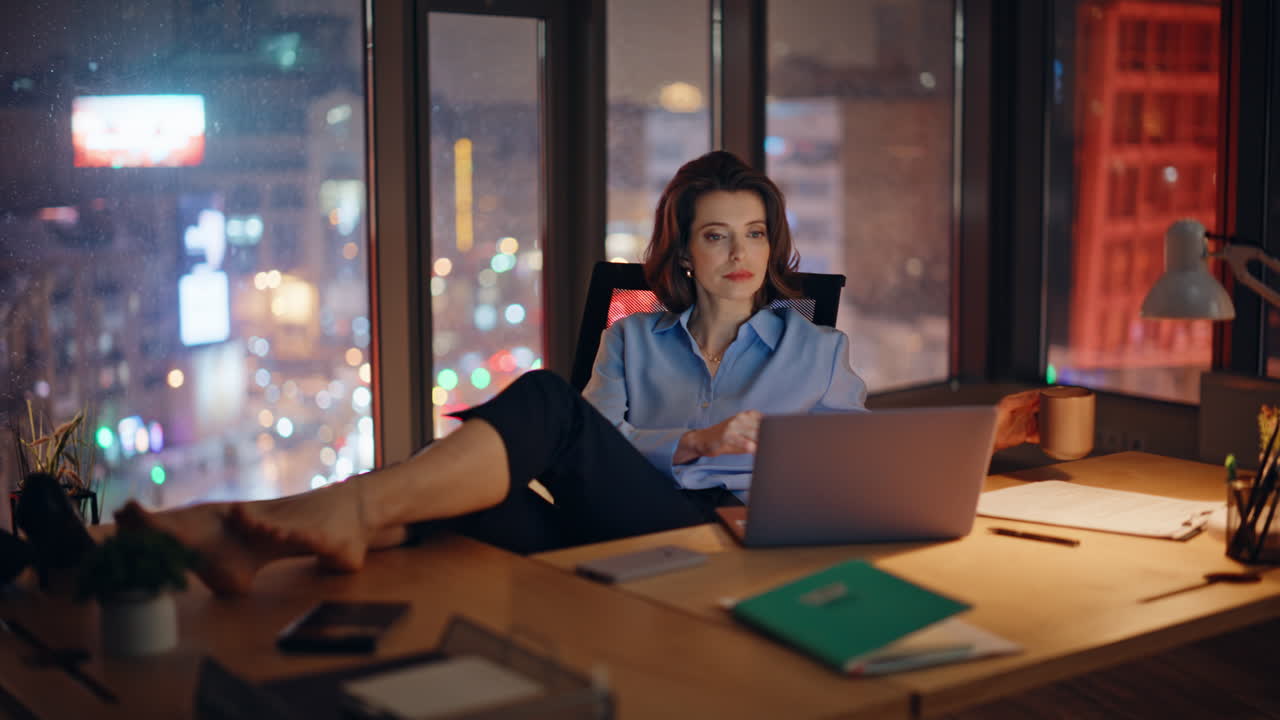 Calm businesswoman drinking coffee sitting night modern office. Elegant woman