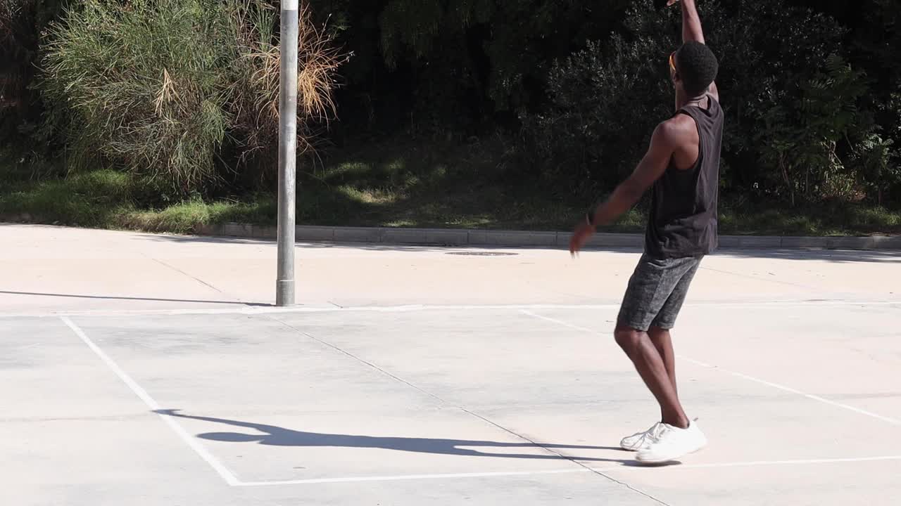 hombre negro jugando al baloncesto en el campo deportivo