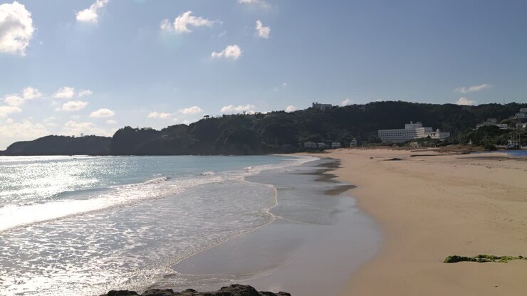 Linda praia de areia ampla e vazia, com ondas em câmera lenta.