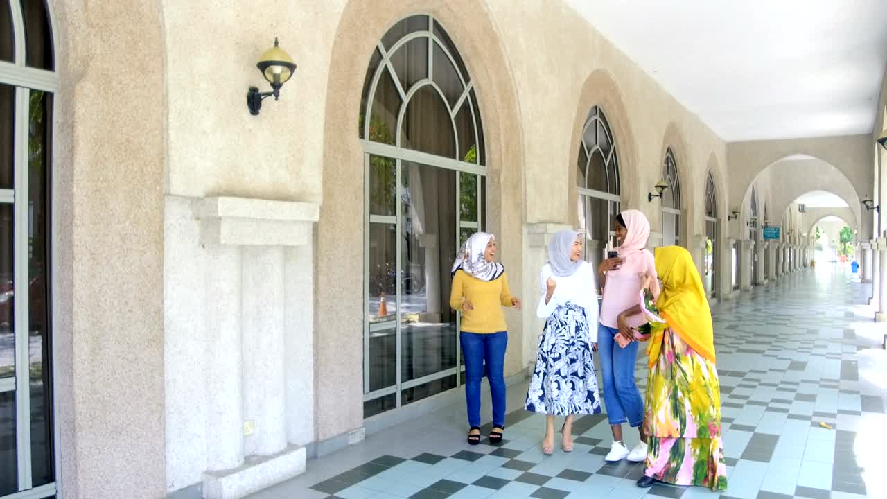 무슬림 대학생들이 걸어서 하이파이브를 하고 축하하고 있습니다.