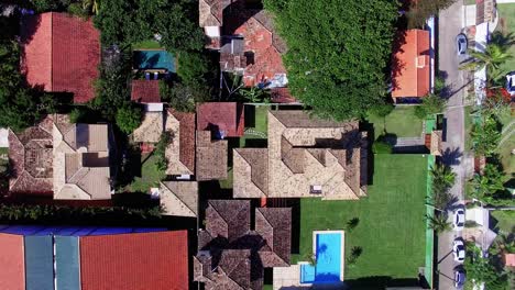 4k bird's eye view of houses in búzios, rio de janeiro, featuring a helipad, captured on a sunny day. the vibrant residential area is surrounded by lush nature, offering a peaceful, upscale atmosphere