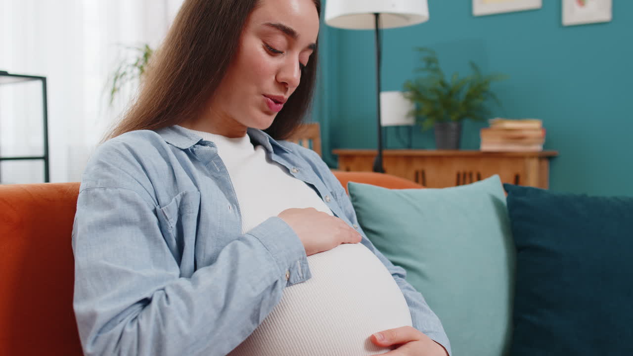 Caucasian pregnant woman future mother singing lullaby and touching big belly talking to unborn baby