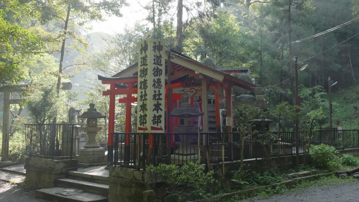 Sole mattutino che splende su un piccolo santuario tradizionale giapponese in una foresta a Fushimi Inari Taisha, Kyoto, Giappone