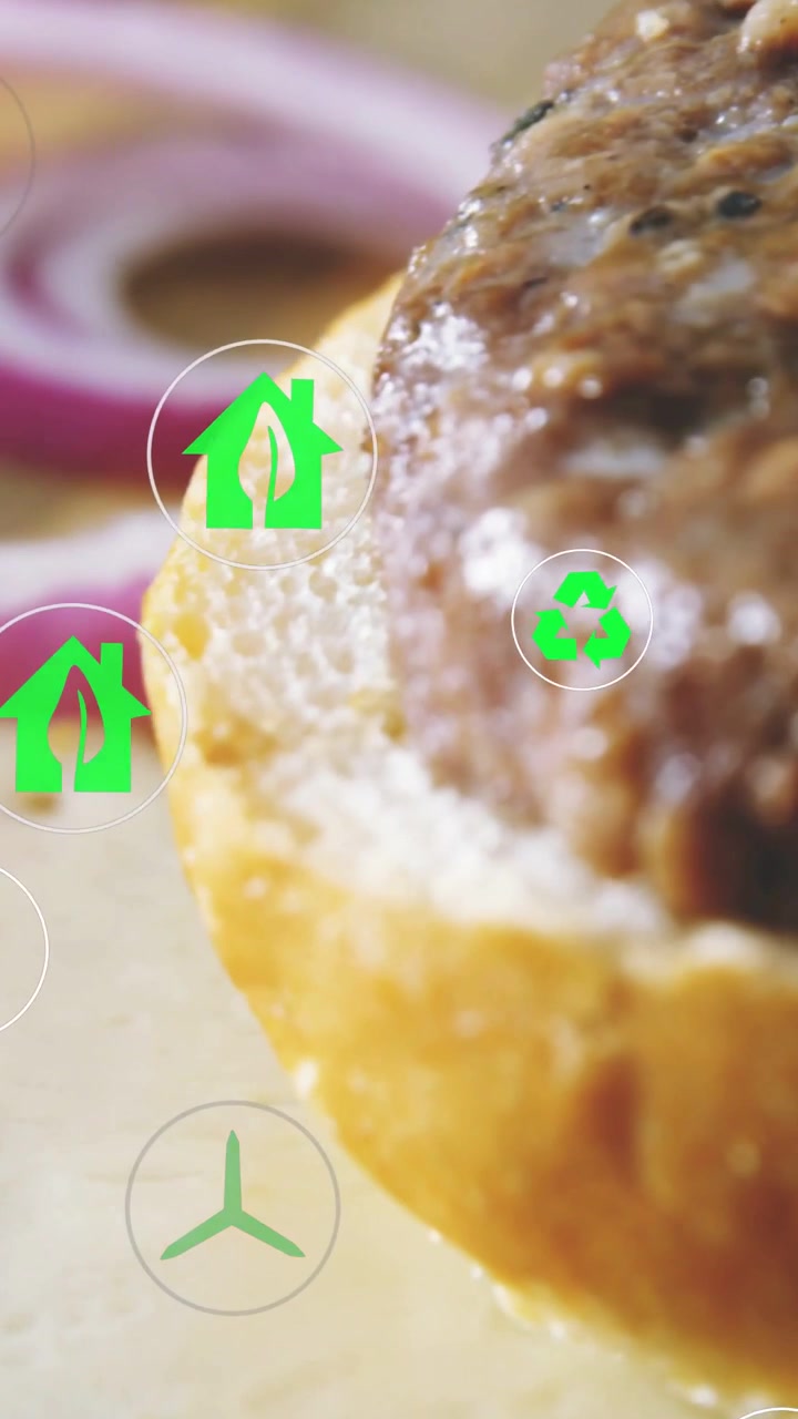 Video verticale: La telecamera si muove, un hamburger che entra, un anello di cipolla visibile, icone ecologiche sopra annunci di cibo.