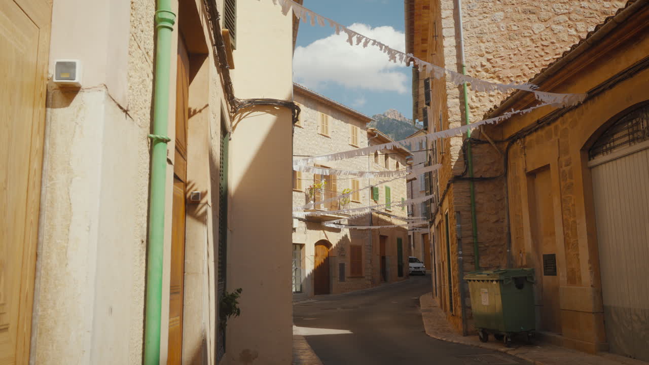 Charmerende smal gade på Mallorca, Spanien, med historisk arkitektur og festlige flag. Perfekt til rejsedokumentarer eller kulturelle udforskningsprojekter