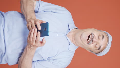 Vertical-video-of-The-old-man-looking-at-the-phone-is-happy.