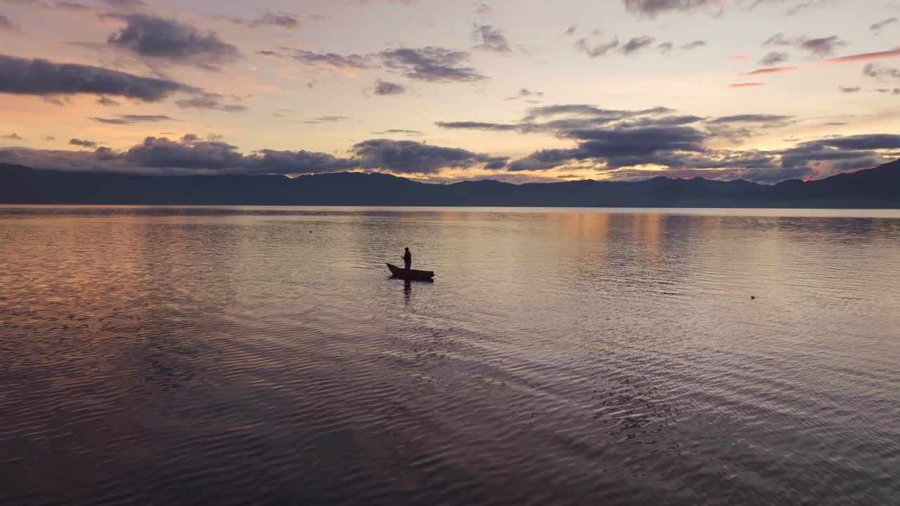작은 보트나 카누를 타고 아란 호수 해가 뜨는 해안에서 시를 하는 사람