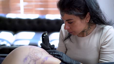 tattooist applying tattoo on hip of anonymous woman in shop