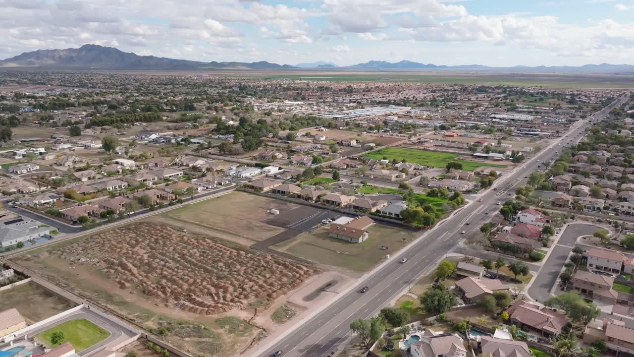 tráfico en la carretera en un suburbio de lujo con villas y mansiones. día nublado en chandler, arizona. tomada amplia. cadena de montañas en la distancia.