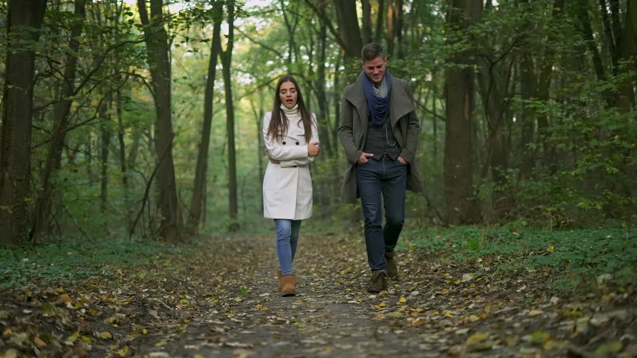 A couple walks together in a forest during autumn