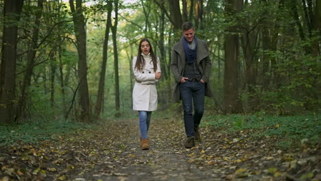 a couple walks together in a forest during autumn