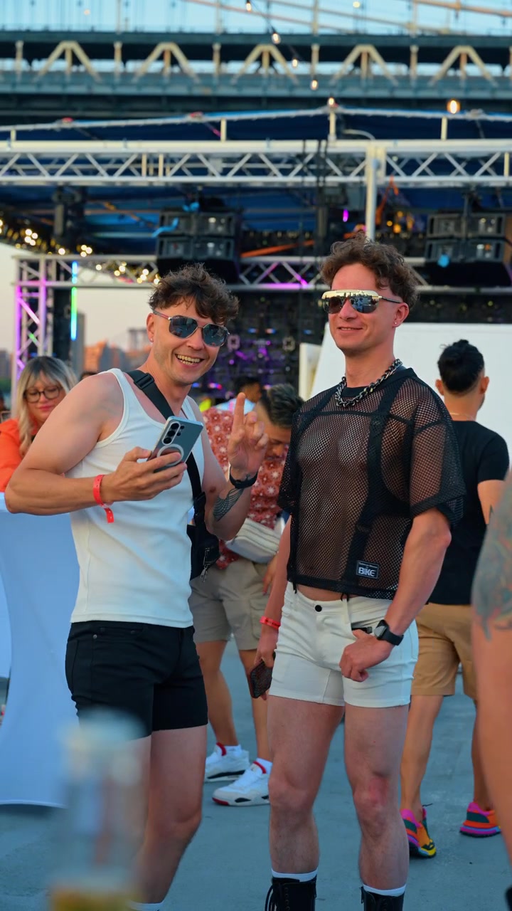Nueva York, EE. UU., 7 de junio de 2026: Hombres tomándose una selfie en un evento de fiesta del orgullo al aire libre. Dos hombres de pie cerca del escenario, uno sostiene un teléfono, iluminación verde, noche de verano.