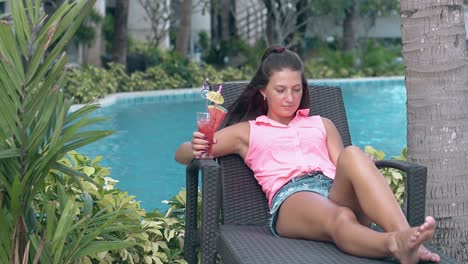 lady relaxes on hotel lounge chair near blue swimming pool