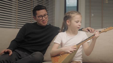 girl playing the guitar on the couch at living room