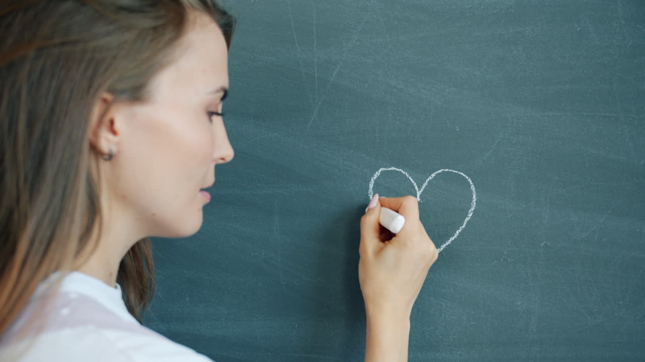 Woman Drawing a Heart on a Chalkboard