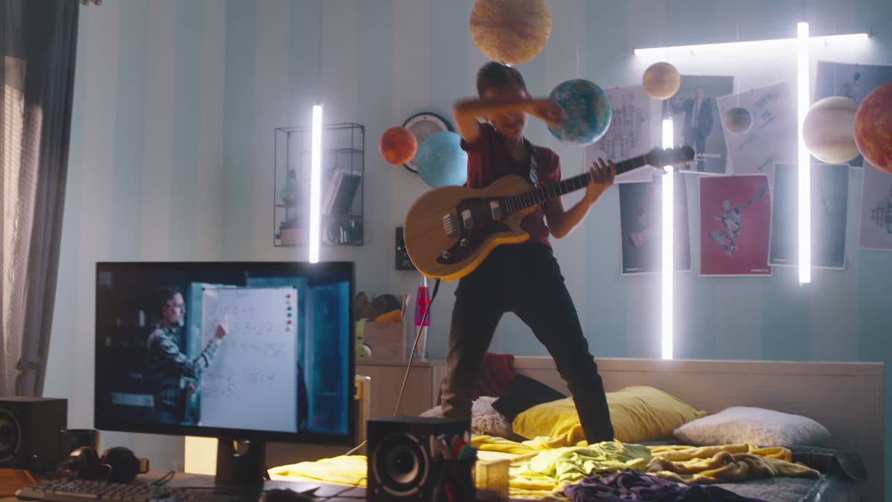 Teenager Playing Guitar in Bedroom While Having Online Math Class
