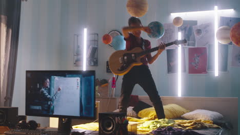teenager playing guitar in bedroom while having online math class