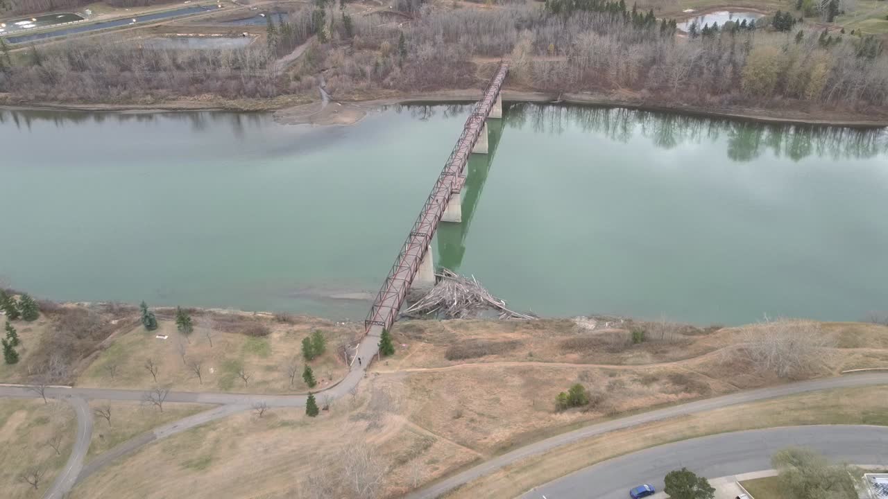vista aérea de pájaros sobre el contaminado río saskatchewan norte en el parque rundel más allá de un puente peatonal vacío y tranquilo junto a casas durante la restricción covid-19 donde se practica el distanciamiento social