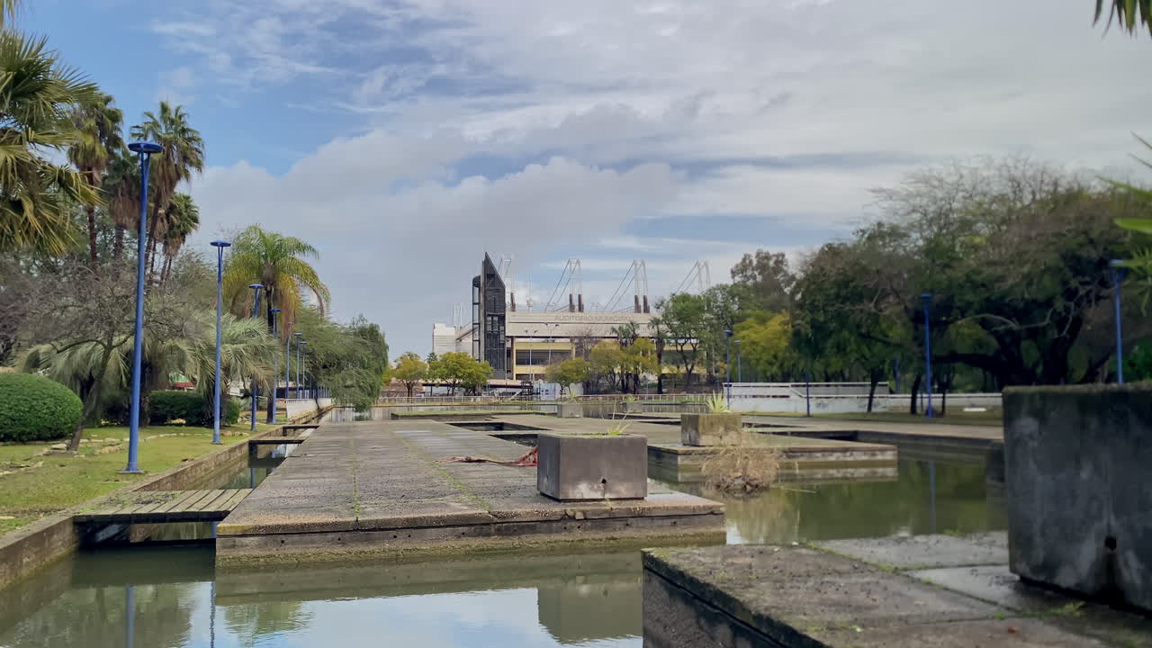 Paesaggio di un parco moderno con tranquilli canali d'acqua, lussureggianti aree verdi, palme e l'architettura prominente del parco a tema Isla Magica.