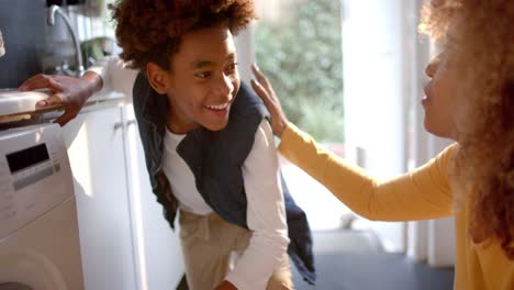 Happy-african-american-mother-and-son-doing-laundry-together,-slow-motion