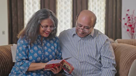 Old-Indian-couple-discussing-old-memories-while-going-through-photo-album