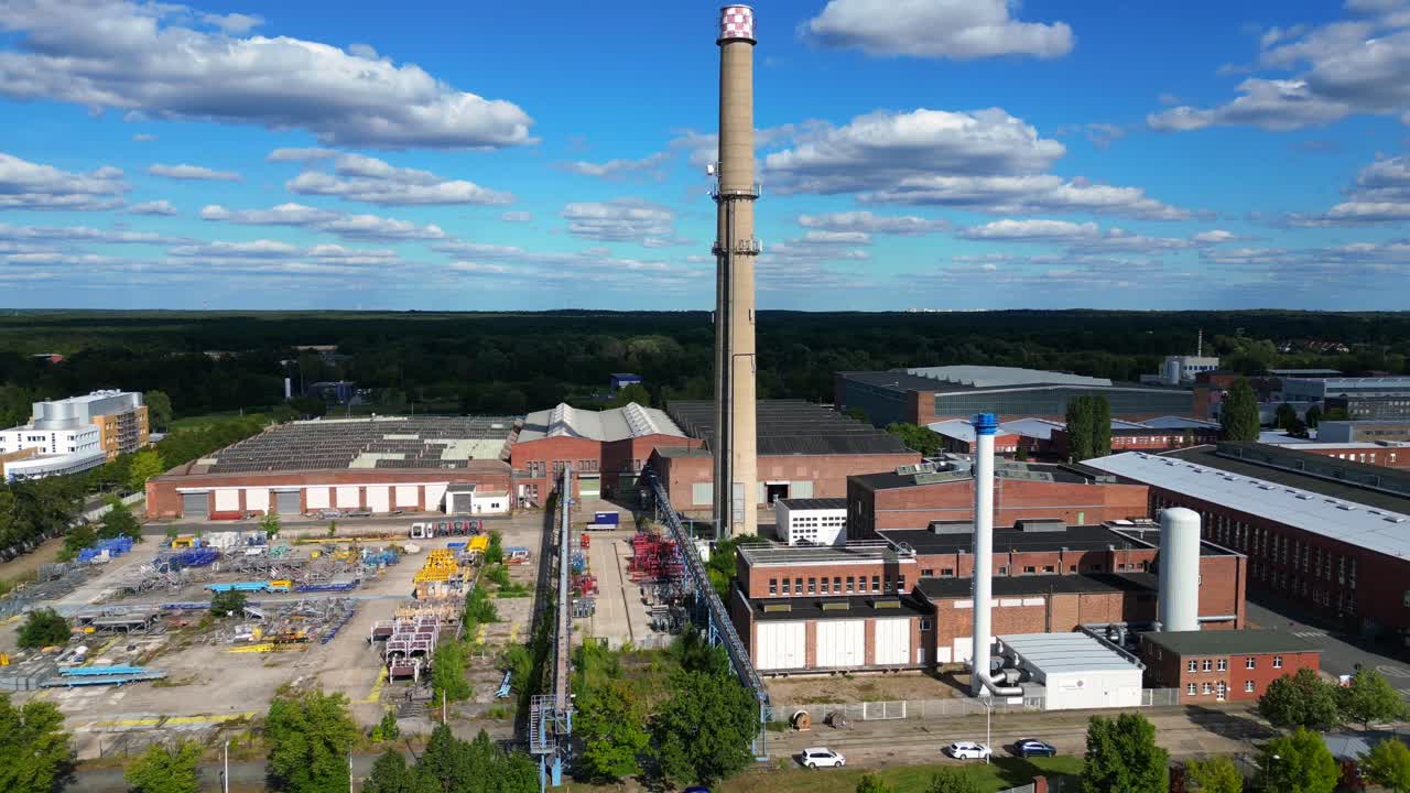 Hennigsdorf steel industry with industrial buildings, chimneys, storage area and a river in the background. Unique aerial view flight descending drone