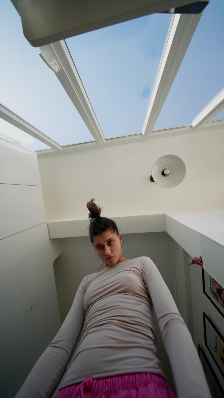 Giovane donna che balla espressivamente sotto un lucernario.