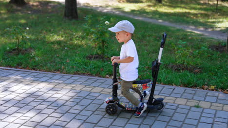 cute caucasian boy riding the scooter. active time in the park on sunny summer day.