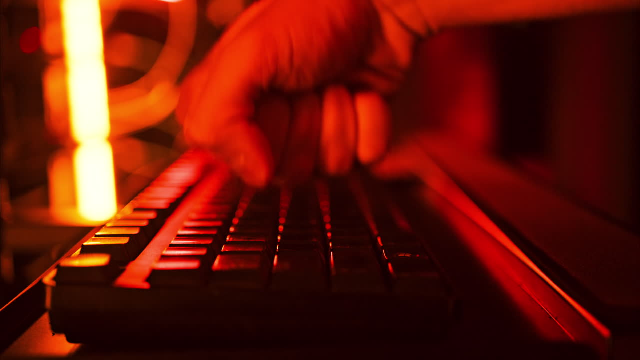 Close up of a man punching the keypad on a computer in a server room with flashing red lights