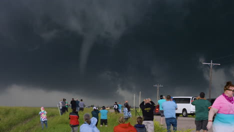 groups of storm chasers watch a tornado move across the road they run to follow the storm