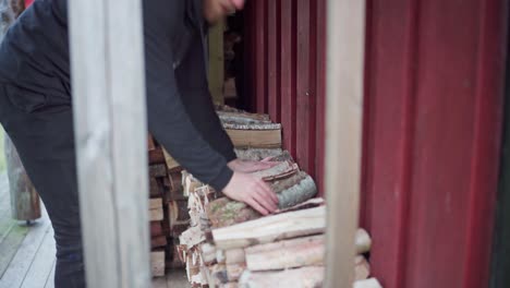 man stacking a pile of firewoods in the cabin