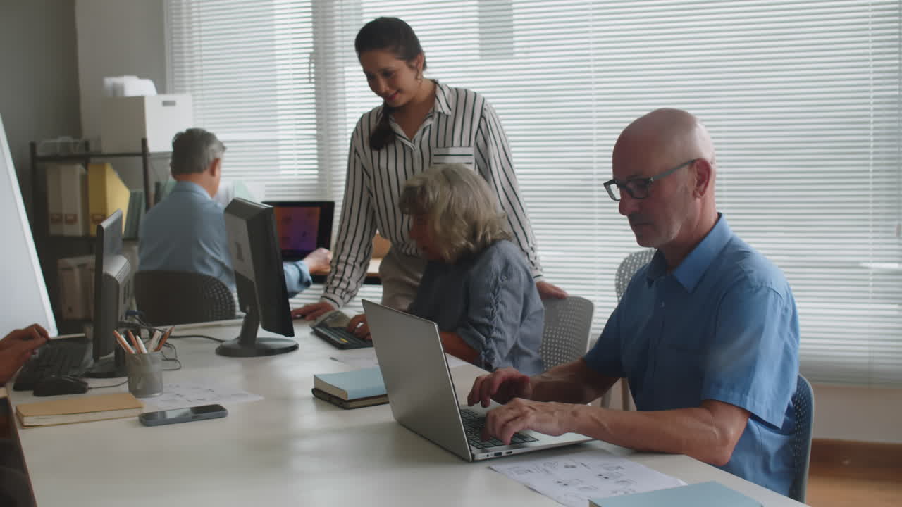 Aged Woman Asking Teacher to Help with Computer at Group Class