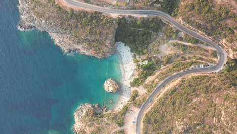 Vista-De-Pájaro-De-Una-Carretera-Sinuosa-Que-Pasa-Por-La-Playa-De-Foneas,-Grecia