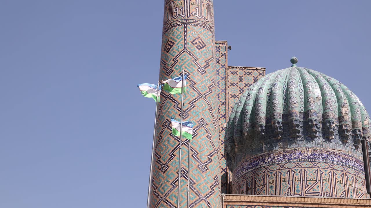 Uzbek flags flying in front of blue tiled domes and minaret in ...