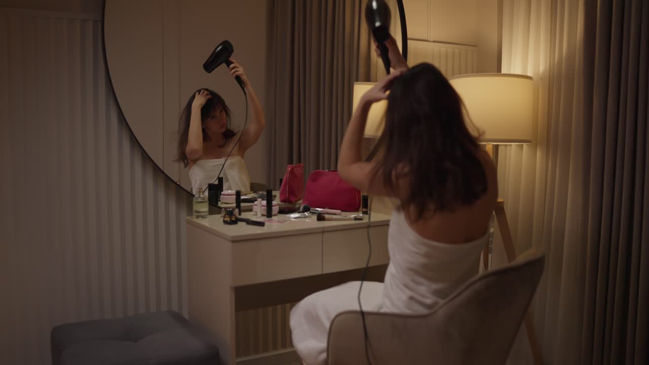 Woman using hair dryer in front of mirror