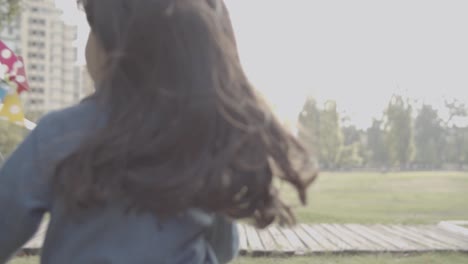 Back-view-of-Latin-girl-holding-paper-fan-and-running-in-the-park